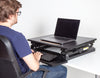 plus, lifestyle image of person sitting at a desk with the desk converter in the low est position.